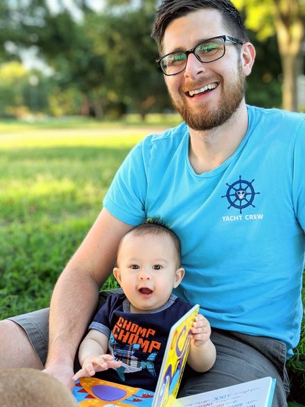 A parent holding a baby and a picture book on a hilltop
